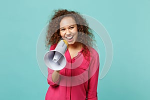 Portrait of cheerful pretty african girl in pink casual clothes scream in megaphone isolated on blue turquoise wall