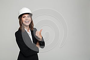 Portrait of a cheerful pretty woman in hard hat and suit