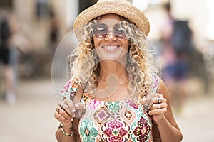 Portrait of cheerful pretty young adult woman smiling and looking on camera. Happy tourist with backpack. Trendy female people