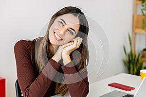 Portrait of cheerful pretty young woman smiling at camera relaxing at workplace