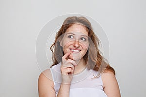 Portrait of cheerful redhead woman thinking looking up and smiling on white background