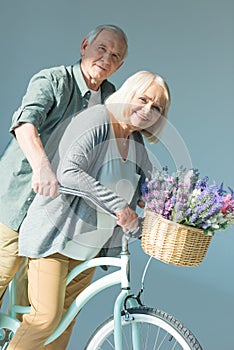 Portrait of cheerful senior couple riding bicycle together