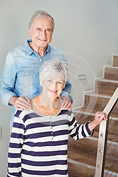 Portrait of cheerful senior couple standing on staircase