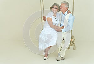Portrait of cheerful senior couple on swing