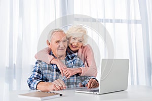 portrait of cheerful senior couple using laptop together