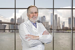 Portrait of cheerful senior doctor with folded arms.