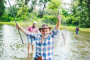Portrait of cheerful senior man fishing. Excited senior man fisherman in cowboy hat with fishing rod, spinning reel on