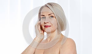 Portrait of cheerful senior woman smiling while looking away at spa. Happy mature woman after spa massage and anti-aging treatment
