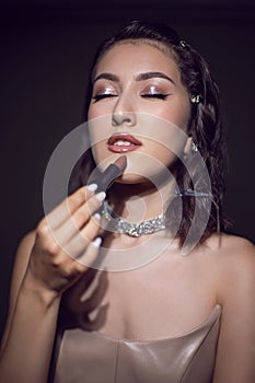 portrait of a cheerful sexy fashionable makeup artist girl in a white skirt stands in the studio and holds lipstick to