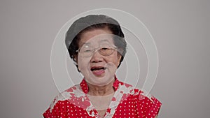 Portrait cheerful smiling Asian senior woman wear glasses grey hair over isolated white background locking the camera and happy