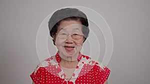 Portrait cheerful smiling Asian senior woman wear glasses grey hair over isolated white background locking the camera and happy