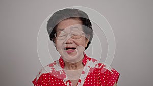 Portrait cheerful smiling Asian senior woman wear glasses grey hair over isolated white background locking the camera and happy