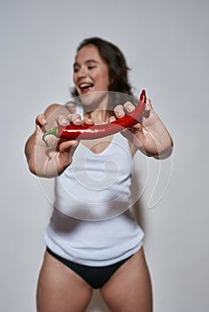 Cheerful woman holding hot pepper,  on white