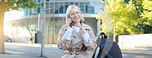 Portrait of cheerful smiling woman, talking on mobile phone, pointing at her smartphone while calling someone, smiling