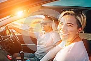Portrait of cheerful smiling young woman with husband have auto journey inside modern car. Safety riding car, car sharing and