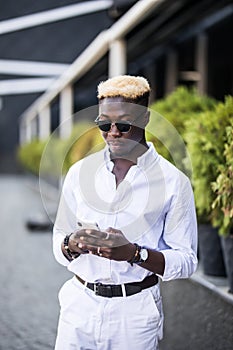 Portrait of cheerful stylish young Afro American man using free city wi-fi while chatting with friends via social networks on cell