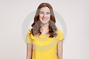 Portrait of cheerful teenager girl in yellow casual T-shirt sincerely smiling at camera, positive
