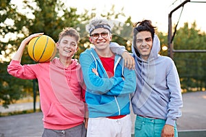 Portrait of cheerful teenagers boys at basketball playground