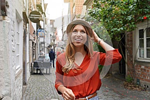 Portrait of cheerful traveler woman walking in Schnoor neighborhood, Bremen, Germany