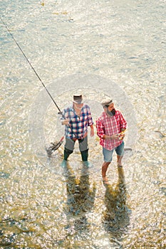 Portrait of cheerful two bearded men fishing. Man fisherman catches a fish. Fly fishing for trout. Angler. Father with