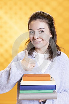 Portrait of cheerful woman carrying stack of books, gathering information