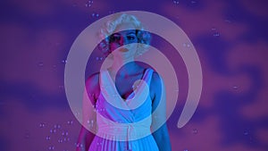 Portrait of a cheerful woman looking like Marilyn Monroe surrounded by soap bubbles close up. Woman in studio with