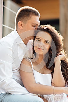 Portrait of cheerful woman and man spending time together and sitting outdoors, hugging and laughing on summer terrace, couple in