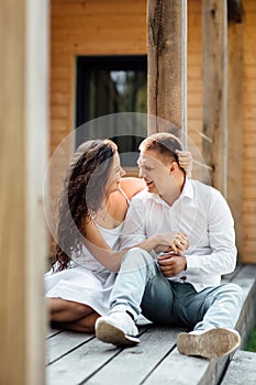 Portrait of cheerful woman and man spending time together and sitting outdoors, hugging and laughing on summer terrace, couple in