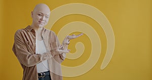 Portrait of cheerful woman pointing sidewards on empty place and smiling on yellow color background