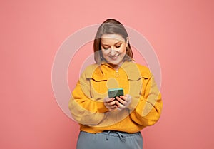 Portrait of cheerful woman using device gadget app smm post isolated over pink color background