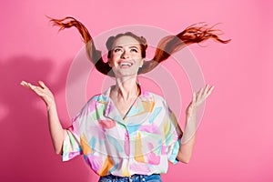 Portrait of cheerful woman wear print shirt hands fluttering foxy hair look up at logo empty space isolated on pink