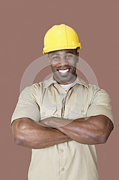 Portrait of cheerful young African construction worker over brown background