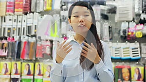 Portrait of cheerful young Asian woman behind counter demonstrating hair dye products