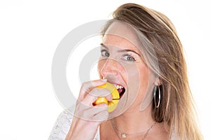 Portrait of cheerful young blonde woman eating bitting yellow apple