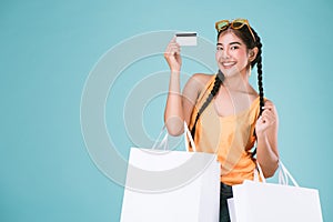 Portrait of cheerful young brunette woman holding credit card and shopping bags.