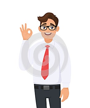 Portrait of a cheerful young business man showing/gesturing/making okay or ok sign with hand and fingers. Human emotions, facial.