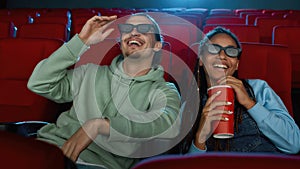 Portrait of cheerful young couple wearing 3d glasses smiling while watching a movie together in cinema auditorium and