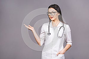 Portrait of cheerful young female doctor with stethoscope over neck looking at camera isolated on grey background