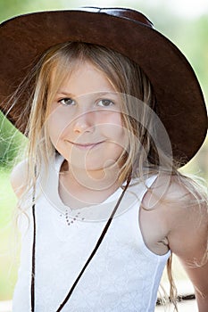 Portrait of cheerful young girl in cowboy leather hat, blond child with smile