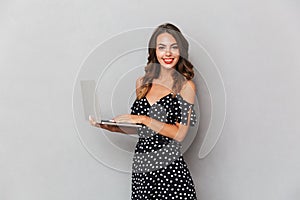 Portrait of a cheerful young girl in dress over gray