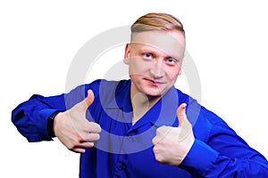 Portrait of a cheerful young guy in a blue shirt shows thumbs up. isolated on white background