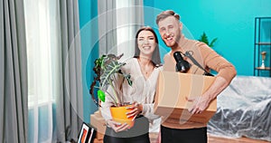 Portrait of cheerful young happy cute family man and woman move in holding cardboard box