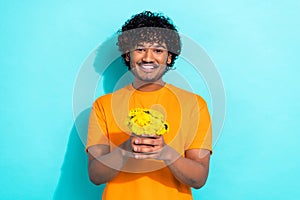 Portrait of cheerful young man holding fresh yellow bouquet daisy flowers send you beautiful present isolated on cyan