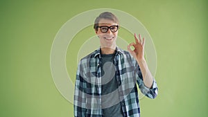 Portrait of cheerful young man showing OK gesture and smiling looking at camera