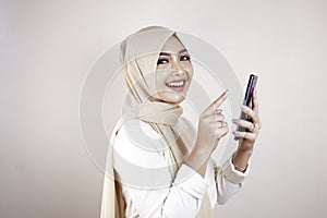 Portrait of cheerful young Muslim Asian woman smiling while looking at her cellphone