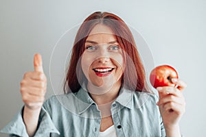 Portrait of a cheerful young woman eating red apple. Healthy nutrition diet. Apple vitamin snack.