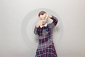 Portrait of cheerful young woman making frame with fingers and smiling