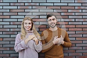 Portrait of cheerful young woman and man dressed sweaters, looking and smiling broadly at camera