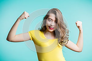 Portrait of cheerful young woman raising her fists with smiling delighted face, yes gesture