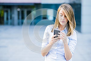 Portrait of cheerful young woman talking on smartphone and laughing outdoors